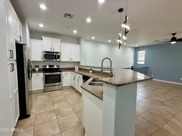 a kitchen with kitchen island stainless steel appliances a sink a stove top oven a refrigerator and cabinets