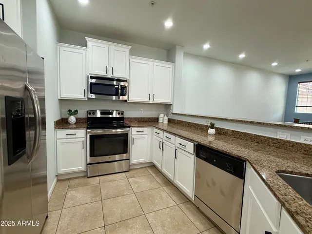 a kitchen with stainless steel appliances granite countertop a stove a sink and a microwave