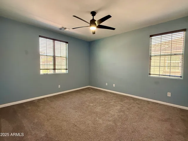an empty room with windows and ceiling fan