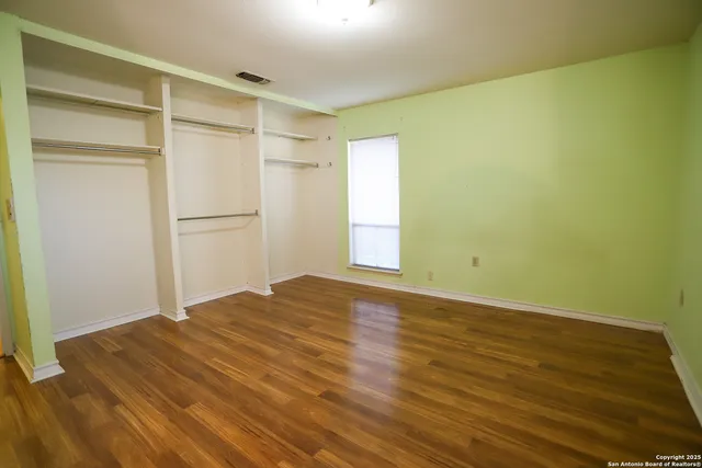 a view of empty room with wooden floor and fan