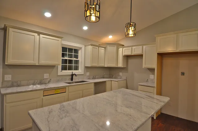 a kitchen with a sink a center island a stove cabinets and stainless steel appliances