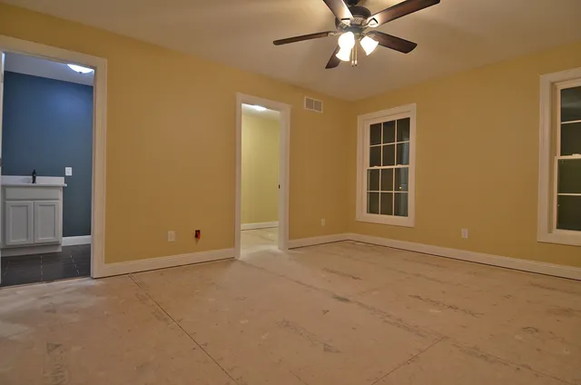 a view of an empty room with window and chandelier fan