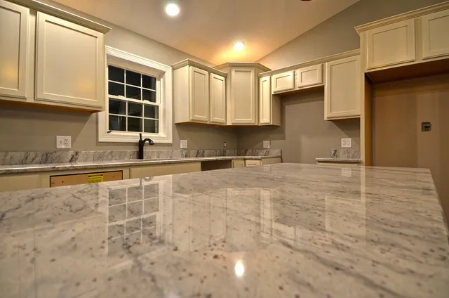 a kitchen with granite countertop a sink a stove and cabinets