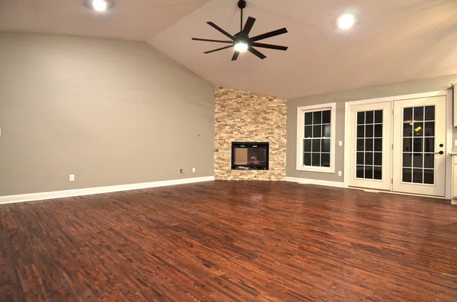 a view of an empty room with wooden floor and a fireplace