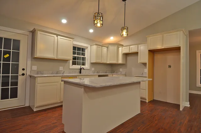 a kitchen with stainless steel appliances granite countertop a sink a stove a refrigerator and island with wooden floor