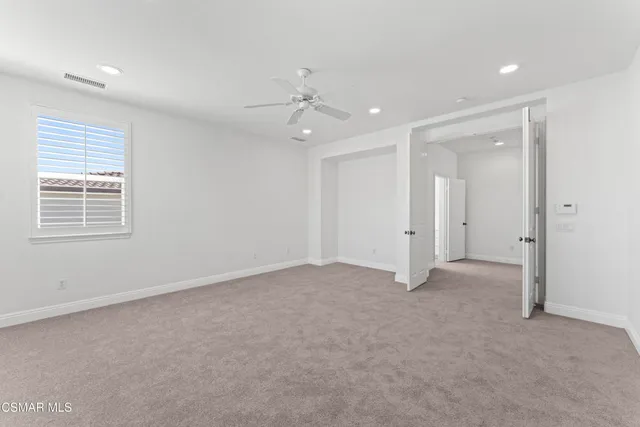 an empty room with chandelier fan and windows