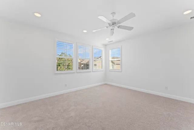 an empty room with windows and fan