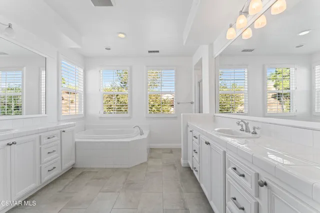 a spacious bathroom with a double vanity sink a large mirror and a bathtub