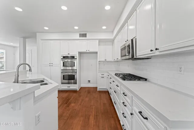 a kitchen with stainless steel appliances granite countertop a stove a sink and a refrigerator