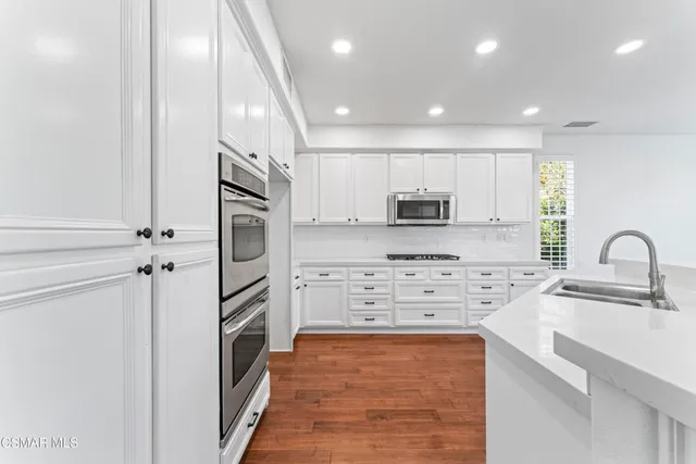 a kitchen with kitchen island a sink stainless steel appliances and cabinets
