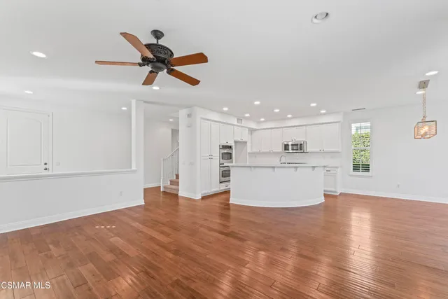 a view of kitchen and empty room with wooden floor