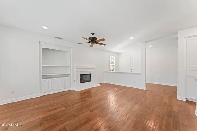 a view of empty room with wooden floor and fireplace