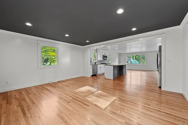 a view of an empty room with kitchen and a window