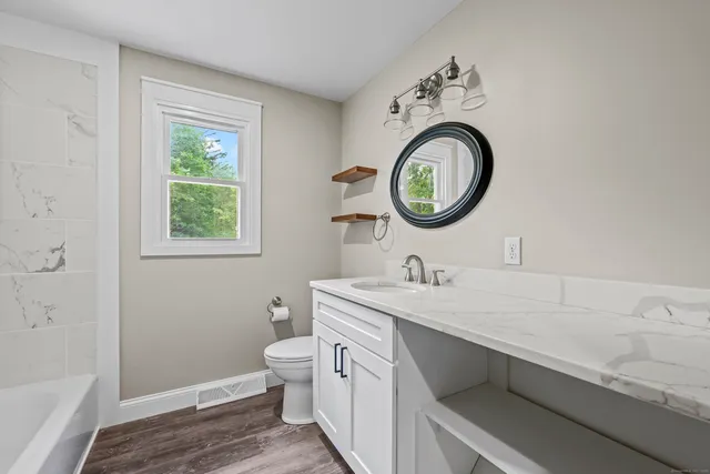 a bathroom with a granite countertop toilet a sink and a mirror