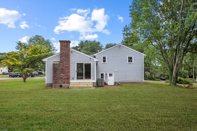 a front view of house with yard and trees in the background