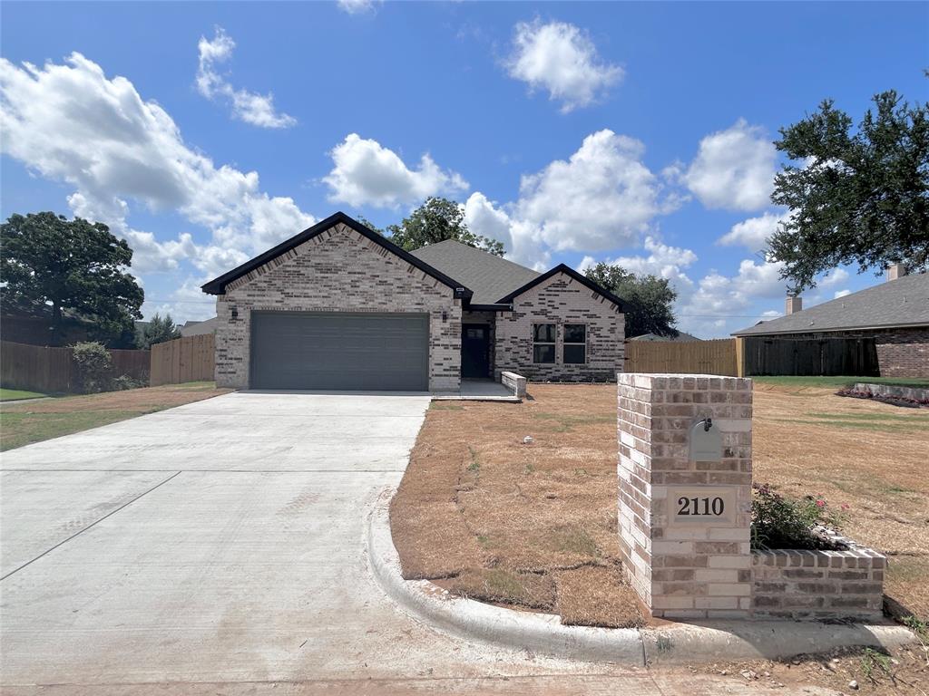 View of front of property with a garage, driveway, and brick siding