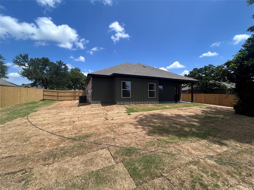 2110 Ridgewood Drive Bridgeport, TX 76426 - Photo 25 of 34 Back of property with board and batten siding, a fenced backyard, and a shingled roof