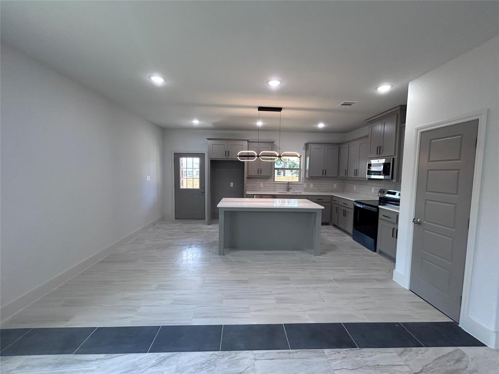 2110 Ridgewood Drive Bridgeport, TX 76426 - Photo 5 of 34 Kitchen with stainless steel appliances, a center island, light countertops, backsplash, and gray cabinets