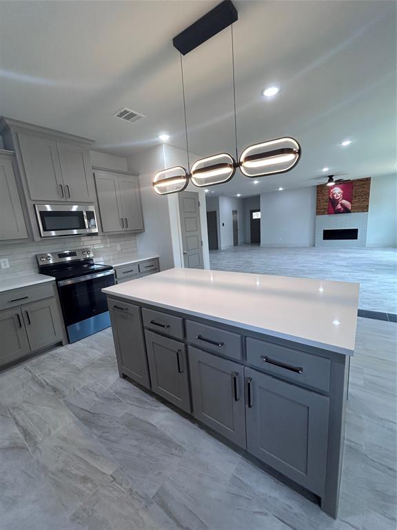 2110 Ridgewood Drive Bridgeport, TX 76426 - Photo 34 of 34 Kitchen with gray cabinets, range, decorative backsplash, light countertops, and open floor plan