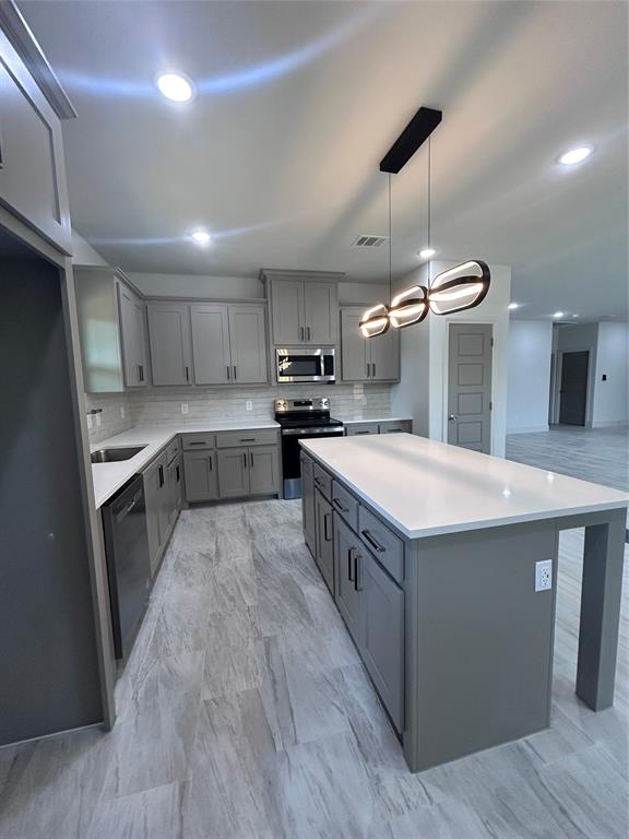 2110 Ridgewood Drive Bridgeport, TX 76426 - Photo 7 of 34 Kitchen featuring gray cabinetry, electric stove, decorative backsplash, a kitchen island, and light countertops