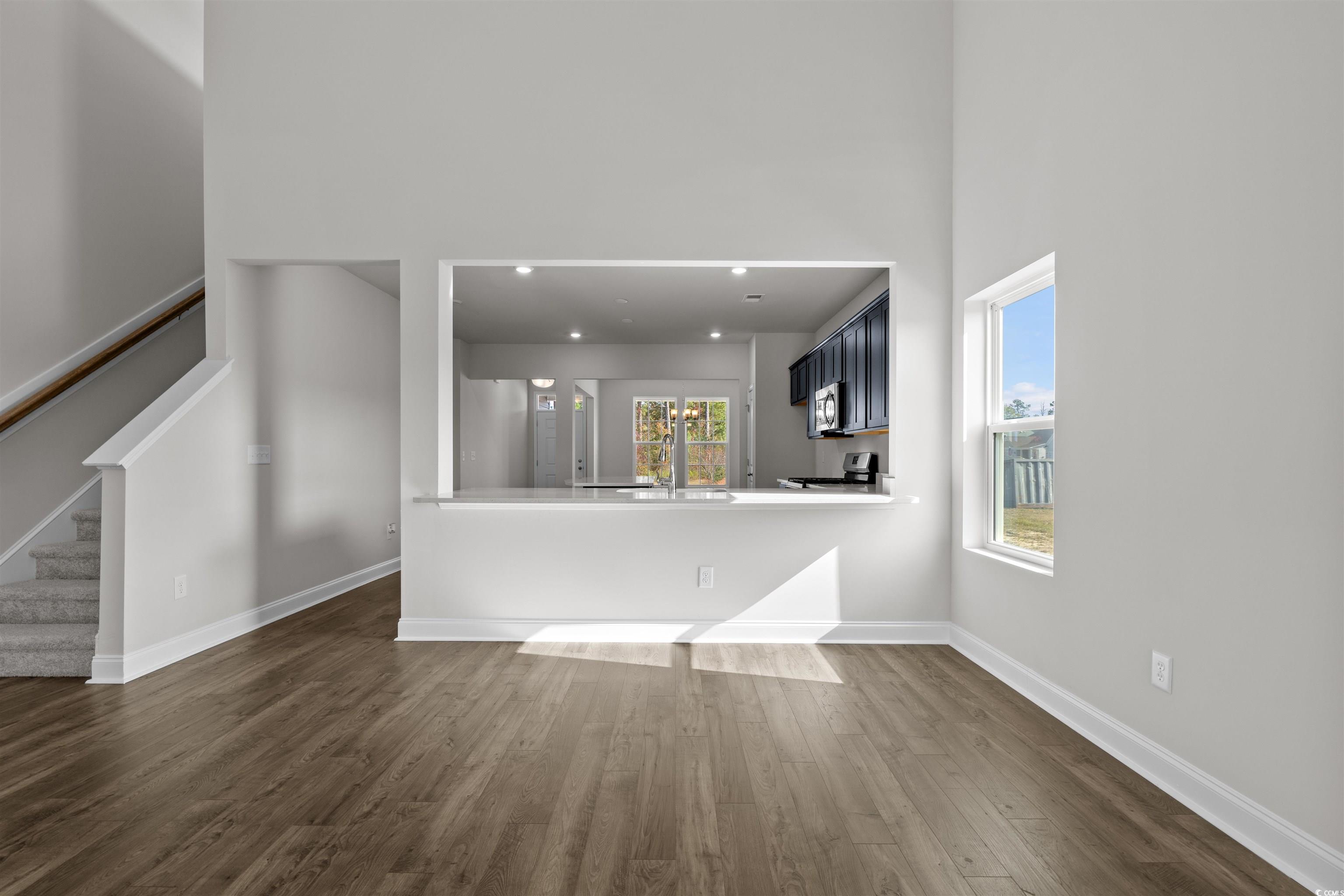 3013 Spain Lane Conway, SC 29527 - Photo 14 of 40 Unfurnished living room featuring stairs, dark wood-style floors, and a towering ceiling