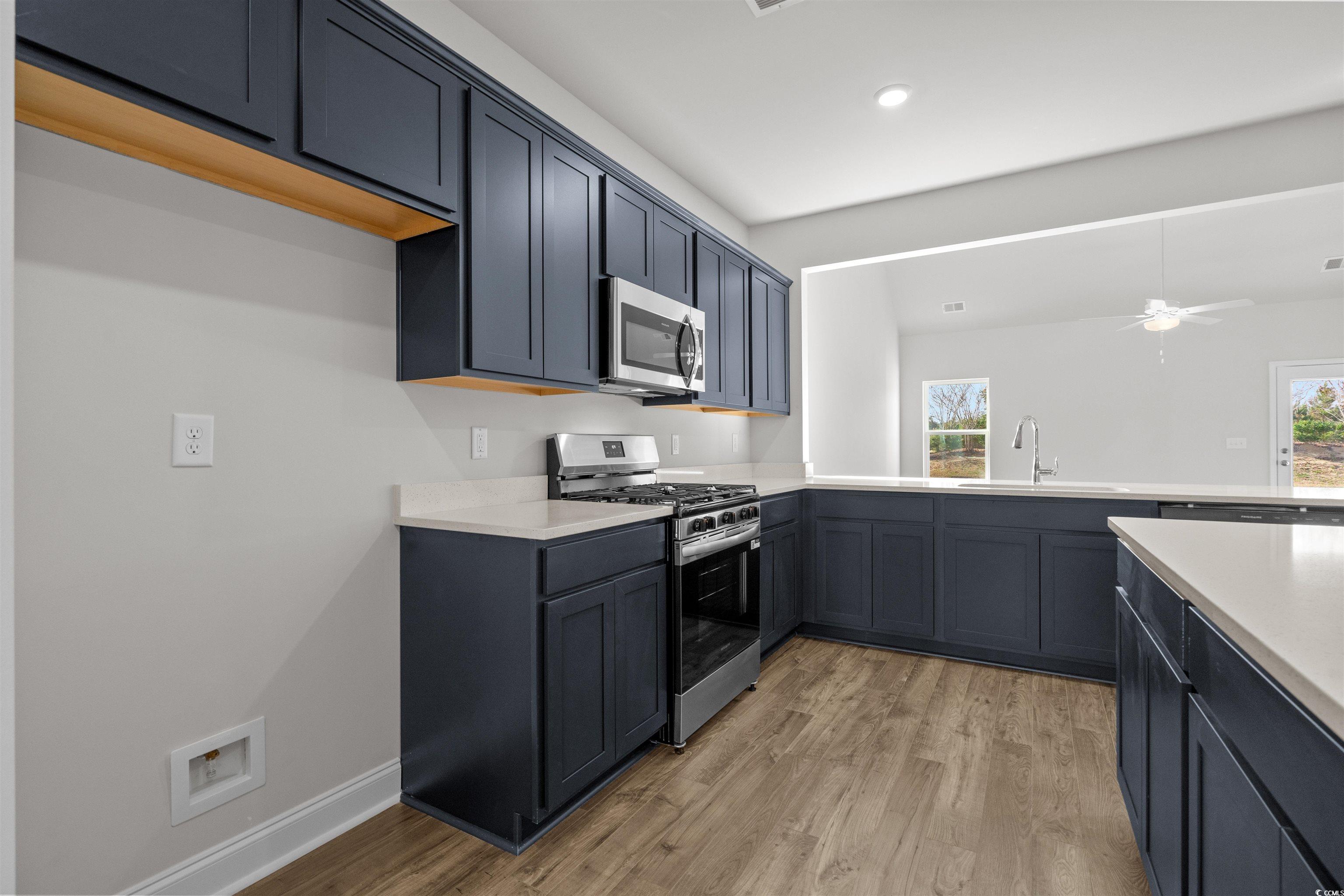 3013 Spain Lane Conway, SC 29527 - Photo 19 of 40 Kitchen featuring appliances with stainless steel finishes, a ceiling fan, light wood-style flooring, and light stone countertops