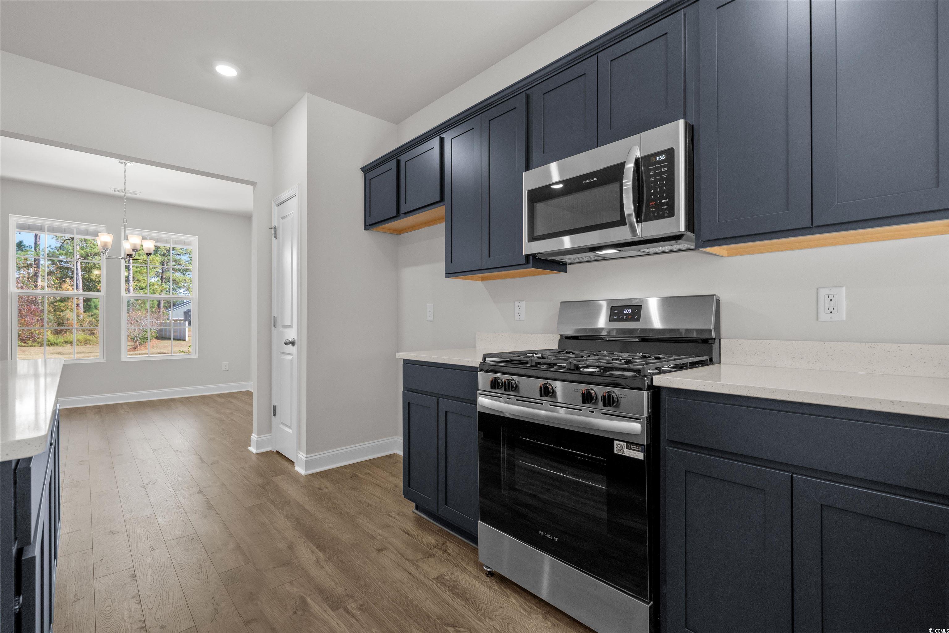 3013 Spain Lane Conway, SC 29527 - Photo 22 of 40 Kitchen with appliances with stainless steel finishes, a chandelier, light stone counters, light wood-style flooring, and decorative light fixtures