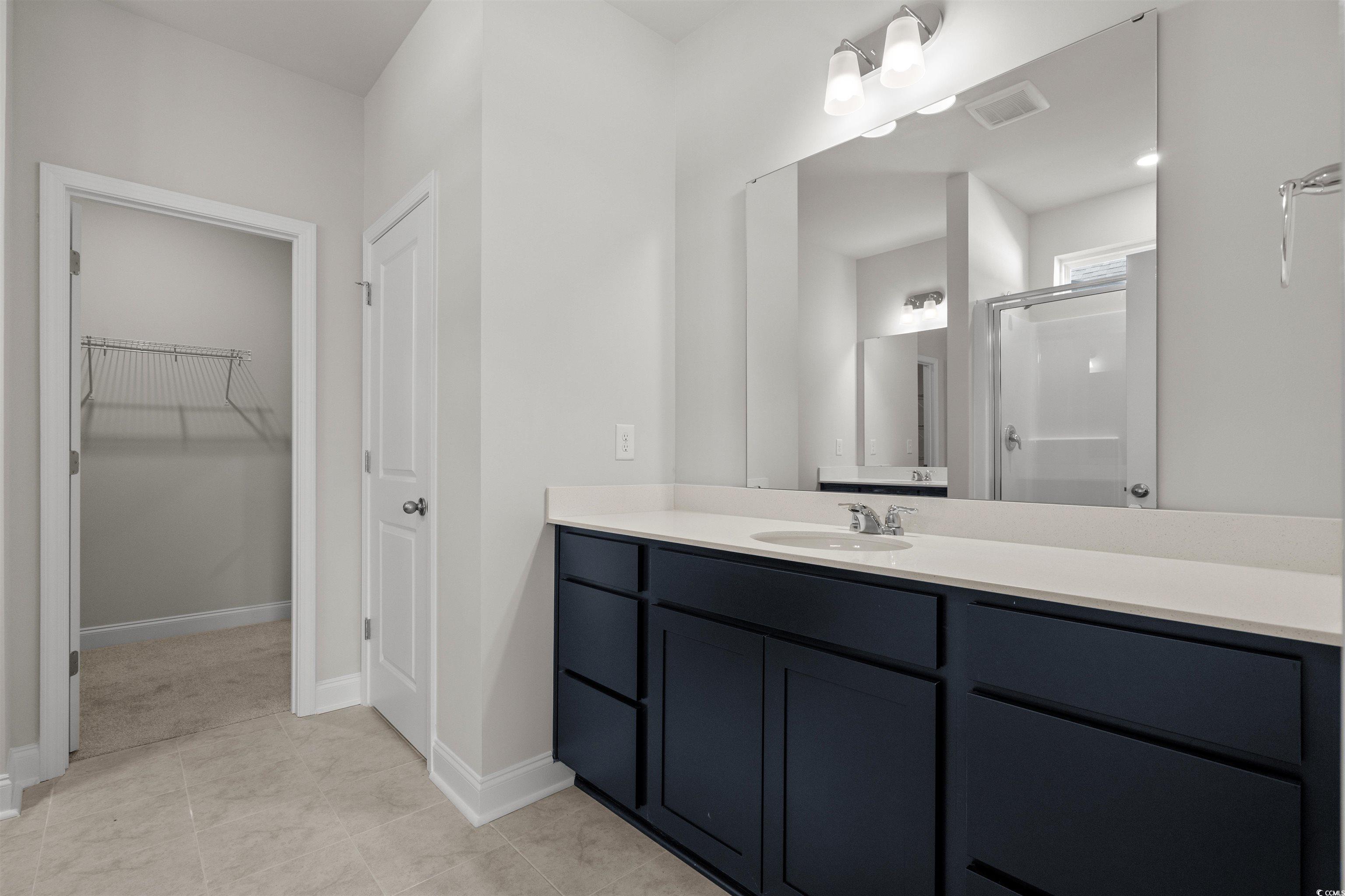 3013 Spain Lane Conway, SC 29527 - Photo 26 of 40 Bathroom featuring vanity, a shower stall, a spacious closet, and light tile patterned floors