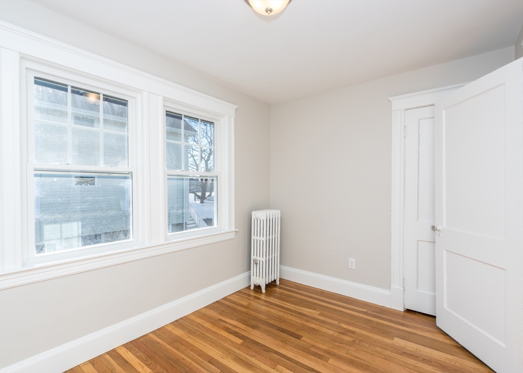 78 Barbara Road, Unit 1 Waltham, MA 02453 - Photo 11 of 15 a view of an empty room with a window and wooden floor