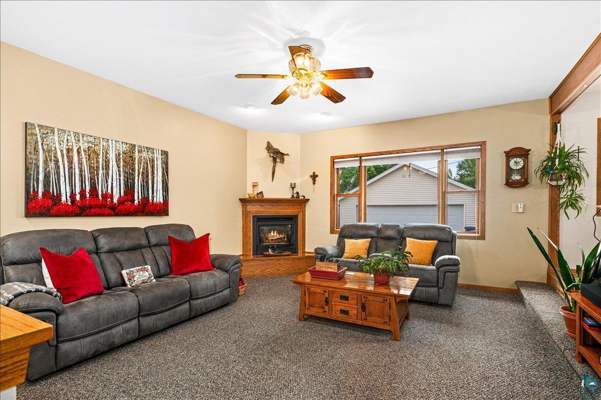 130 West Austin Street Duluth, MN 55803 - Photo 4 of 35 Spacious living area featuring neutral-toned walls, a corner fireplace with a wooden mantel, and a ceiling fan with integrated lighting