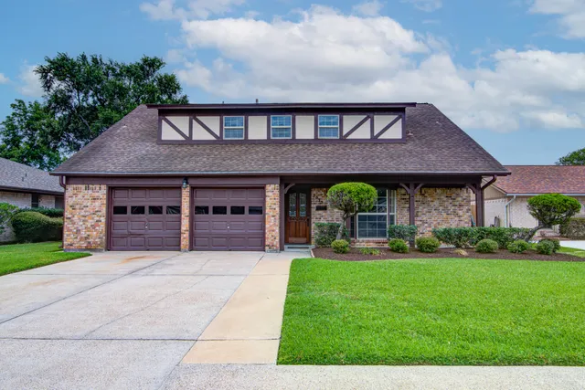 a front view of a house with garden and trees