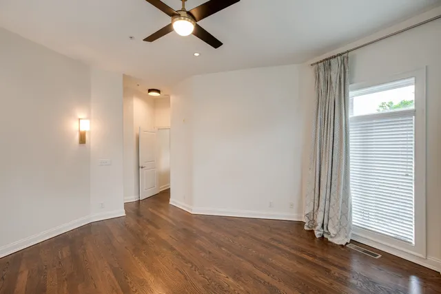 an empty room with wooden floor cabinet and windows