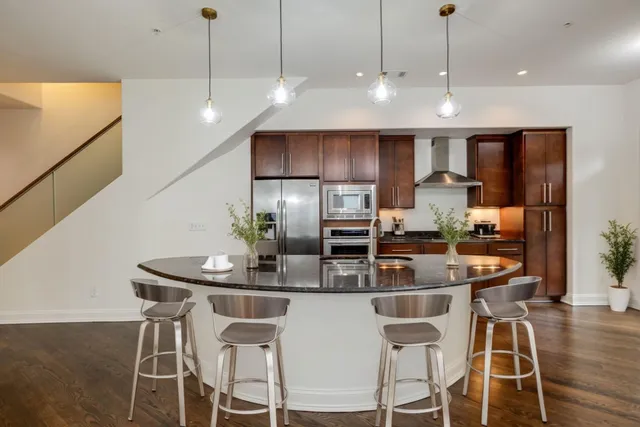 a kitchen with stainless steel appliances a dining table chairs and stove top oven