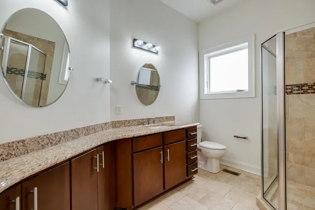 a bathroom with a granite countertop toilet a sink and a mirror