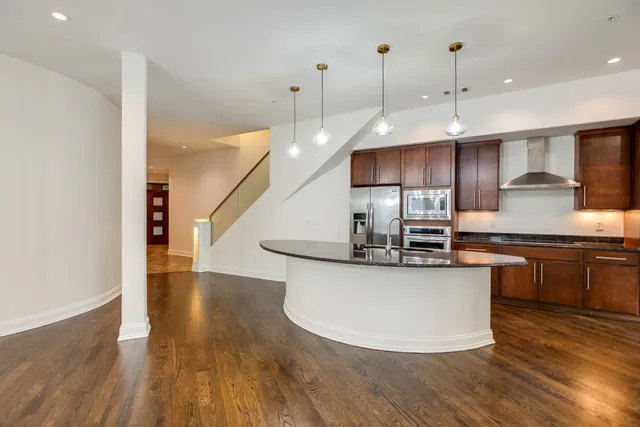 a kitchen with stainless steel appliances granite countertop a sink a stove and a wooden floors