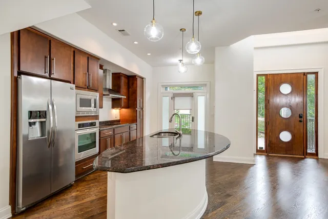 a kitchen with stainless steel appliances granite countertop a refrigerator a stove and a wooden floors
