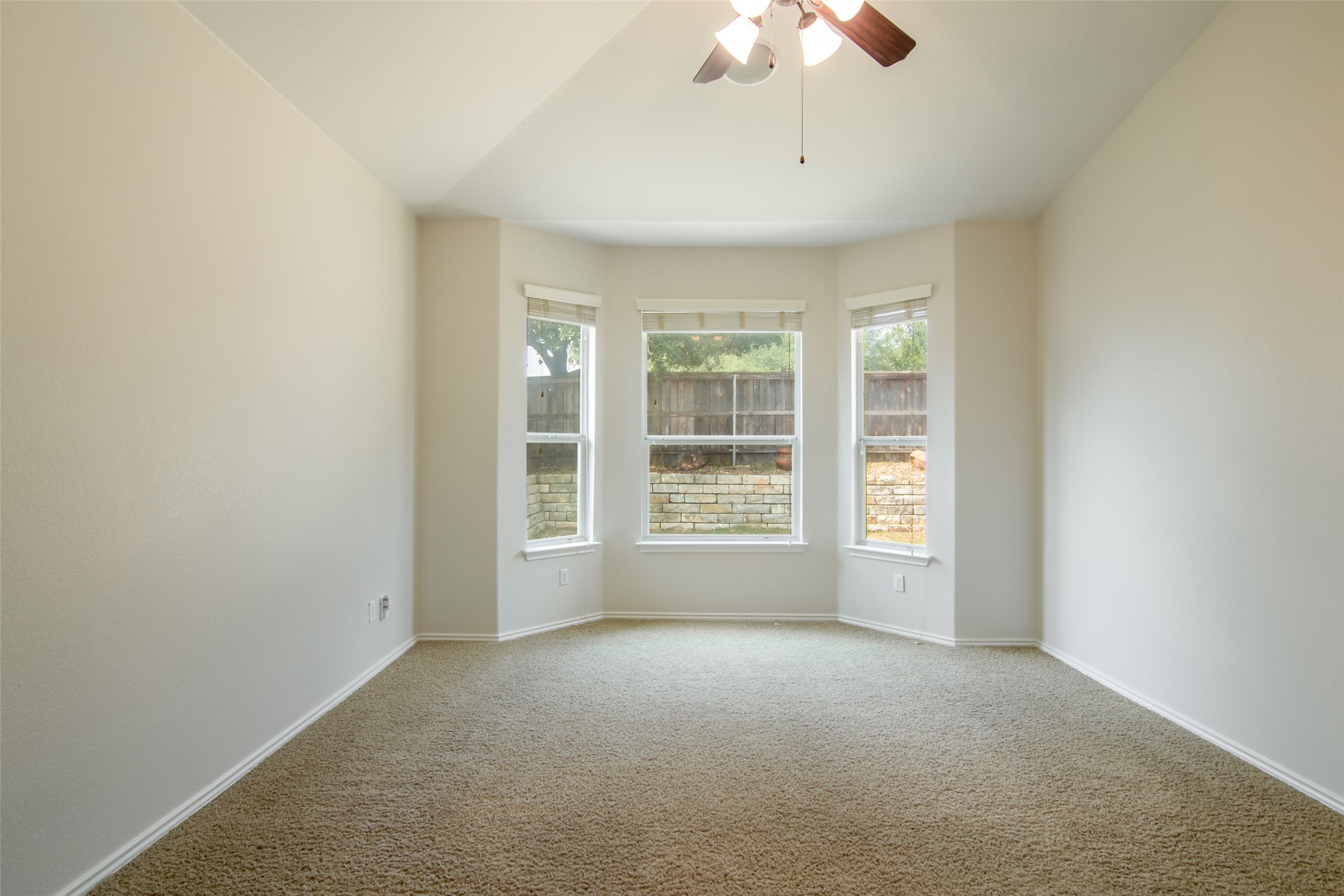 12104 Broten Street Austin, TX 78748 - Photo 16 of 32 A spacious room with a vaulted ceiling and bay windows overlooks a fenced outdoor area.