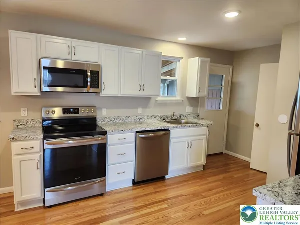 a kitchen with stainless steel appliances granite countertop a stove a sink and a microwave