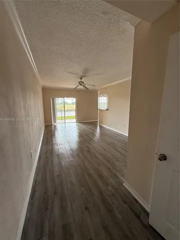 an empty room with wooden floor and kitchen view