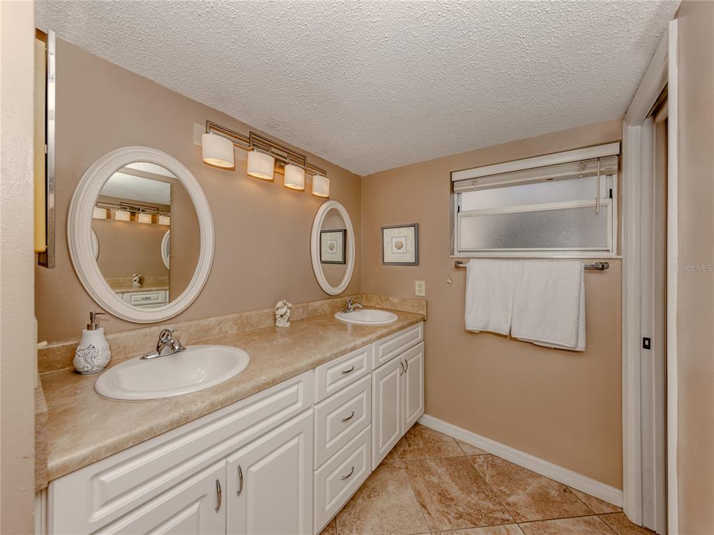 437 Cerromar Lane, Unit 312 Venice, FL 34293 - Photo 18 of 68 a bathroom with a granite countertop double vanity and a mirror