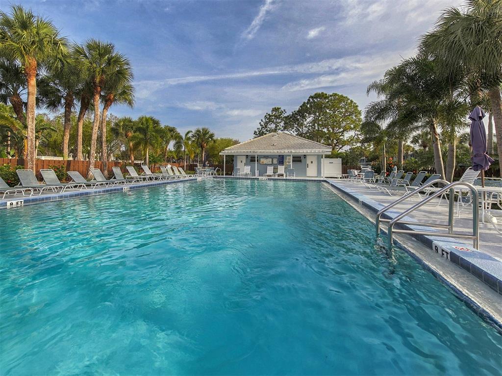 437 Cerromar Lane, Unit 312 Venice, FL 34293 - Photo 2 of 68 a view of a swimming pool with a lawn chairs under palm trees