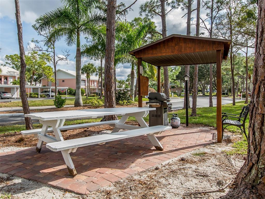 437 Cerromar Lane, Unit 312 Venice, FL 34293 - Photo 39 of 68 a view of a yard with a table and chairs under an umbrella