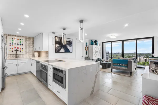 a large white kitchen with a large window and stainless steel appliances