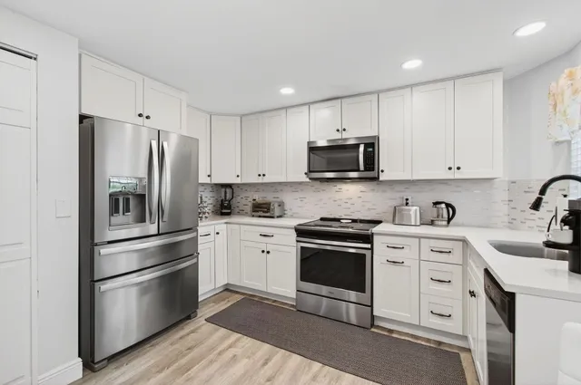 a kitchen with cabinets stainless steel appliances and sink