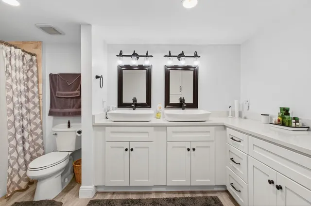 a bathroom with a double vanity sink mirror and toilet