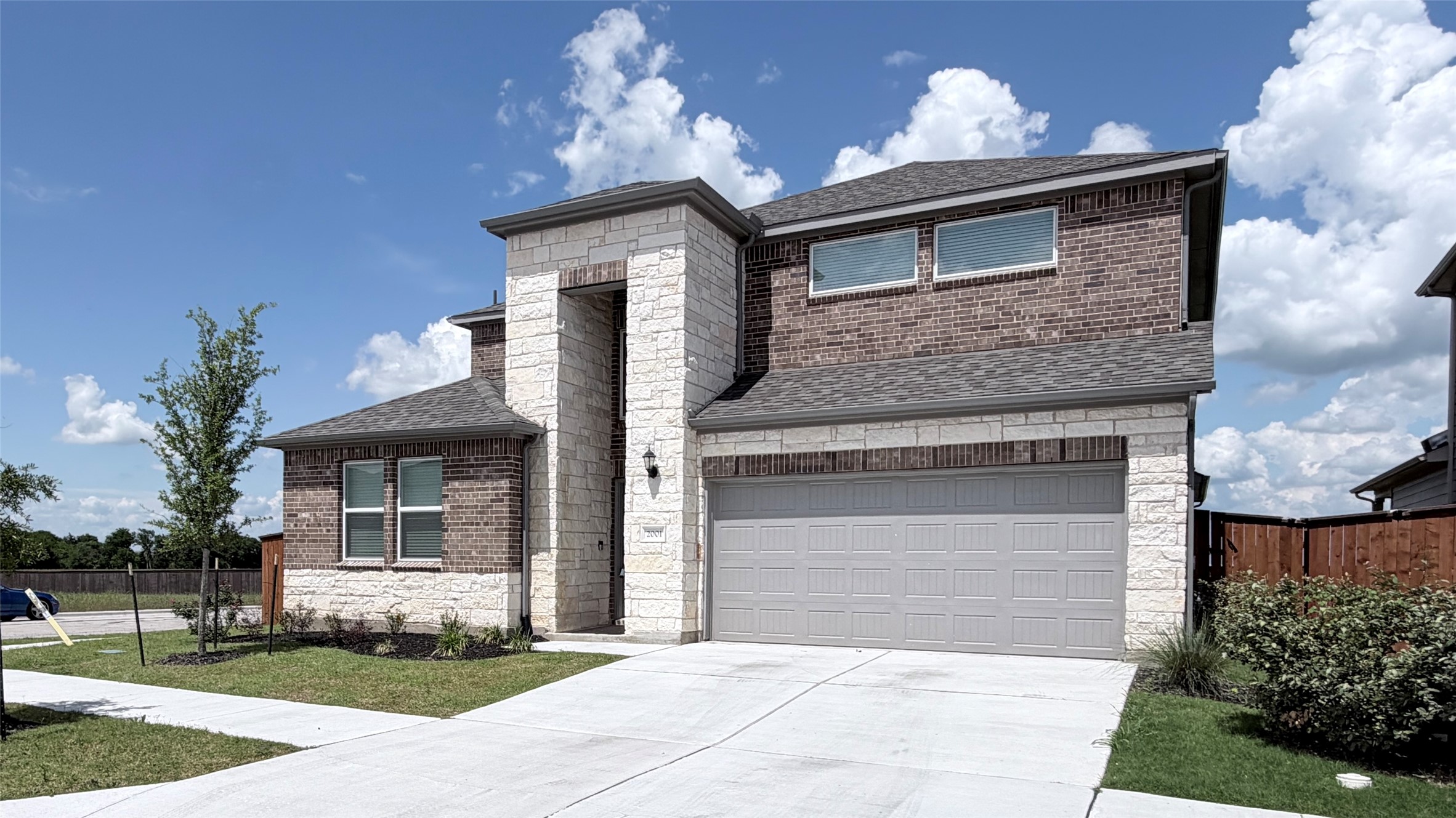 2001 Wynn Road Hutto, TX 78634 - Photo 3 of 39 A well-maintained facade features a mix of brick and stone, complete with a two-car garage and tidy landscaping.