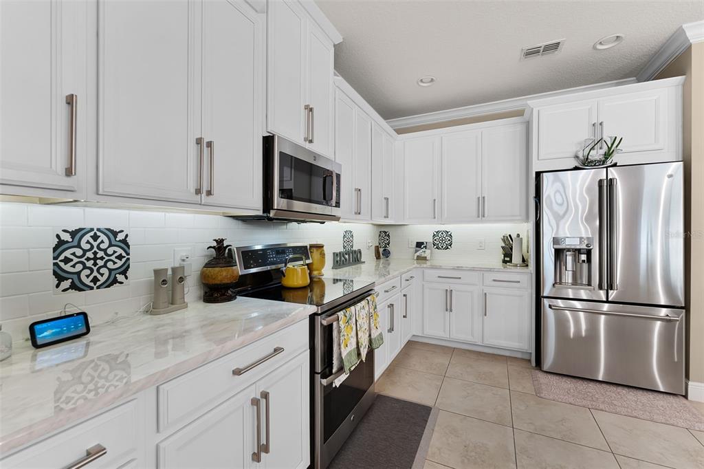 1208 Fieldstone Circle Oviedo, FL 32765 - Photo 12 of 43 a kitchen with granite countertop a refrigerator a sink and white cabinets