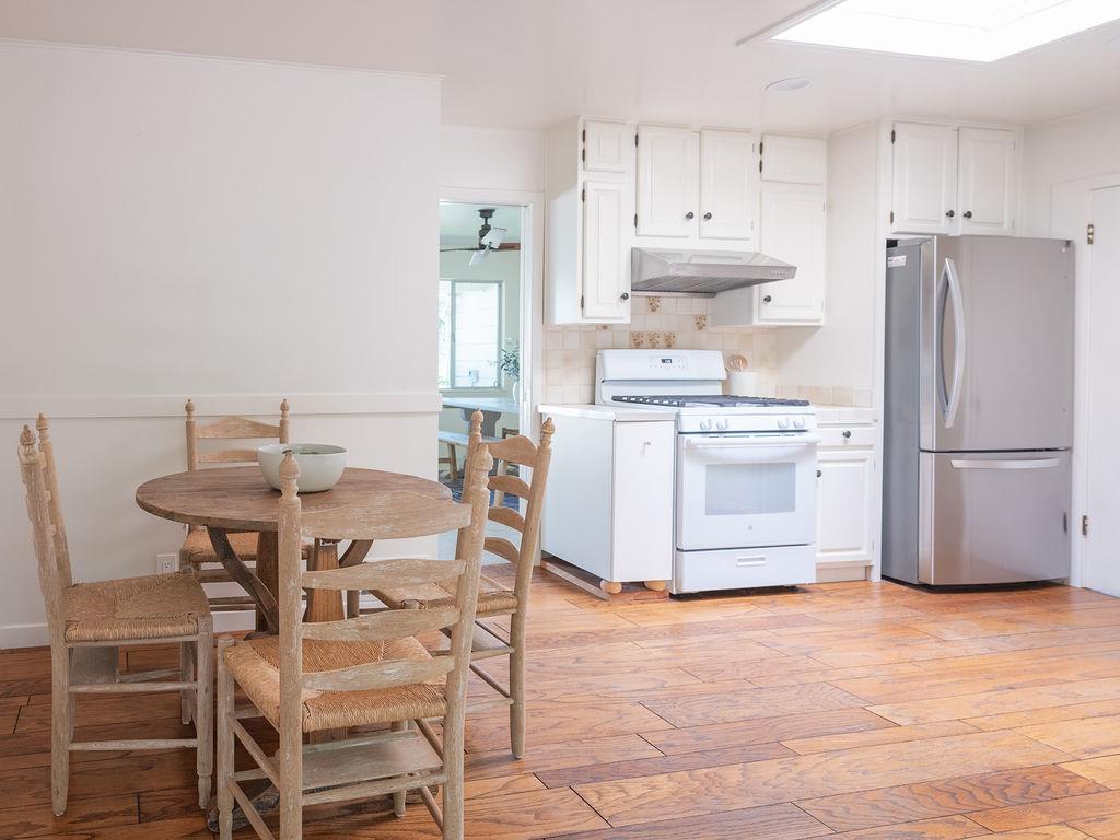 264 Upland Road Redwood City, CA 94062 - Photo 7 of 31 a kitchen with stainless steel appliances a stove a refrigerator and white cabinets with wooden floors