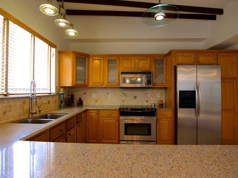 7975 Sunset Drive Miami, FL 33143 - Photo 6 of 21 a kitchen with stainless steel appliances granite countertop a sink a stove and a refrigerator