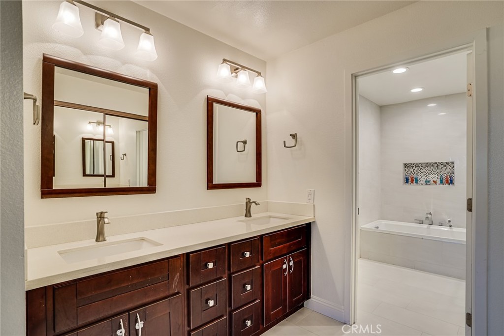 49 East Yale Loop, Unit 26 Irvine, CA 92604 - Photo 39 of 63 a bathroom with double vanity sinks double vanity tub and mirrors